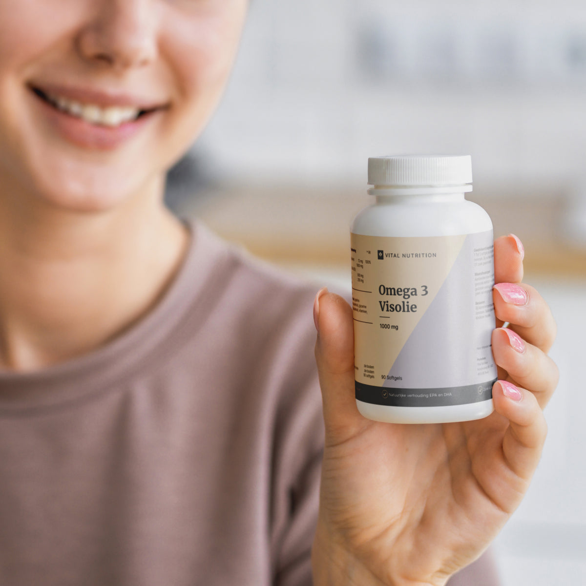 Vrouw houdt Omega 3 Visolie 100 mg van Vital Nutrition vast in product close up