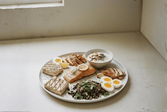 Bord met verschillende eiwitrijke voeding zoals zalm, kip, bonen, tofu, eieren en kwark met noten en zaden