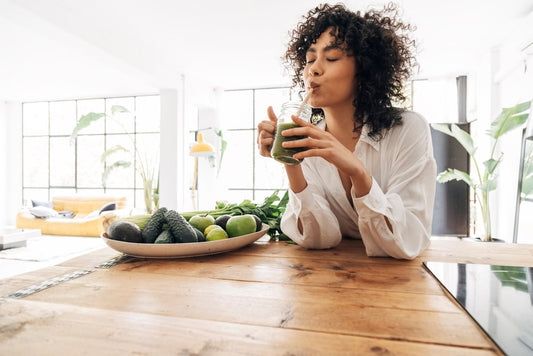 Gezonde vrouw in keuken drinkt green juice