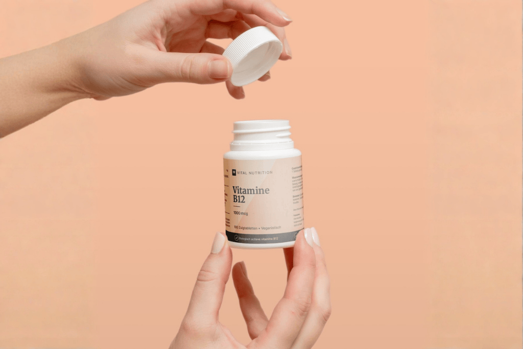 Potje Vitamine B12 van Vital Nutrition in hand met gekleurde achtergrond