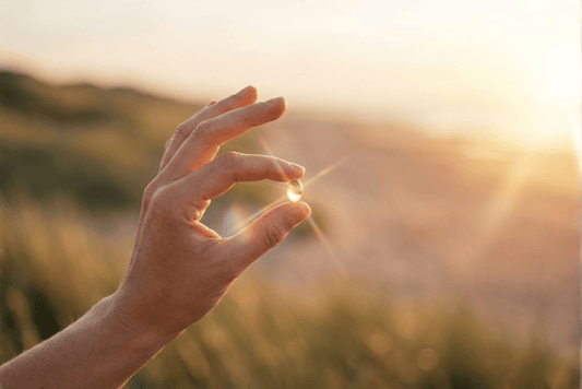 Hand met vitamine D softgel in zonlicht