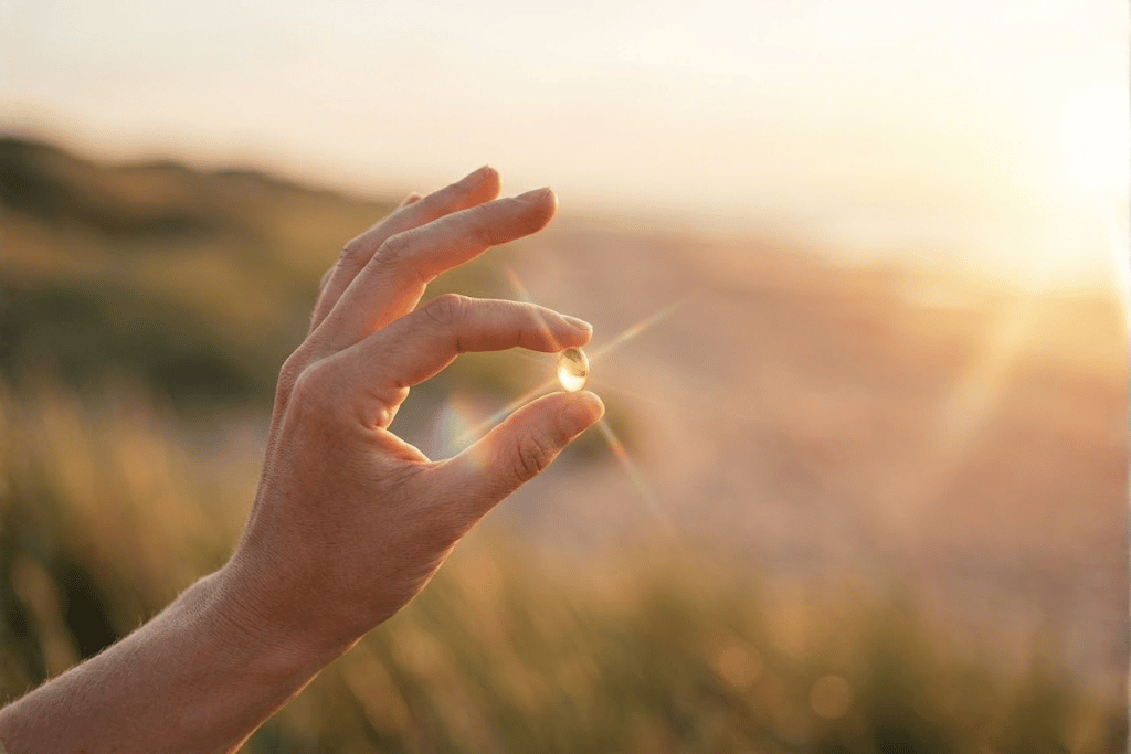 Hand met vitamine D softgel in zonlicht