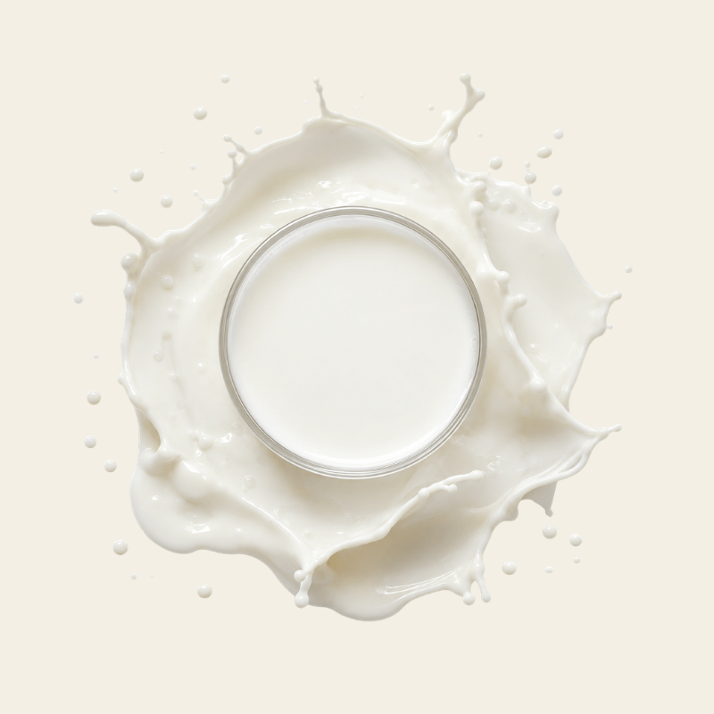 Transparant glazen schaaltje gevuld met romige witte melk met spatten en druppels als bron van colostrum