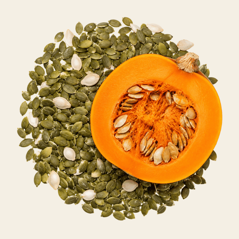 Gehalveerde pompoen met diep oranje vruchtvlees en losse olijfgroene pompoenzaden