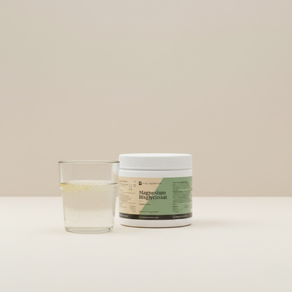 Magnesium Bisglycinaat Poeder van Vital Nutrition op een beige minimalistische studio ondergrond met een gevuld glas water op de voorgrond