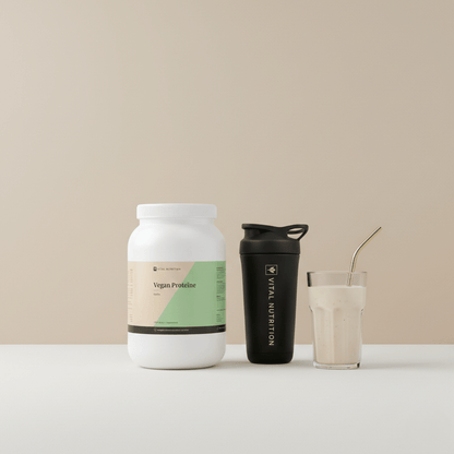 Vegan Proteïne van Vital Nutrition op een beige minimalistische studio ondergrond met de Vital Shaker en een gevuld glas met een shake erin op de voorgrond