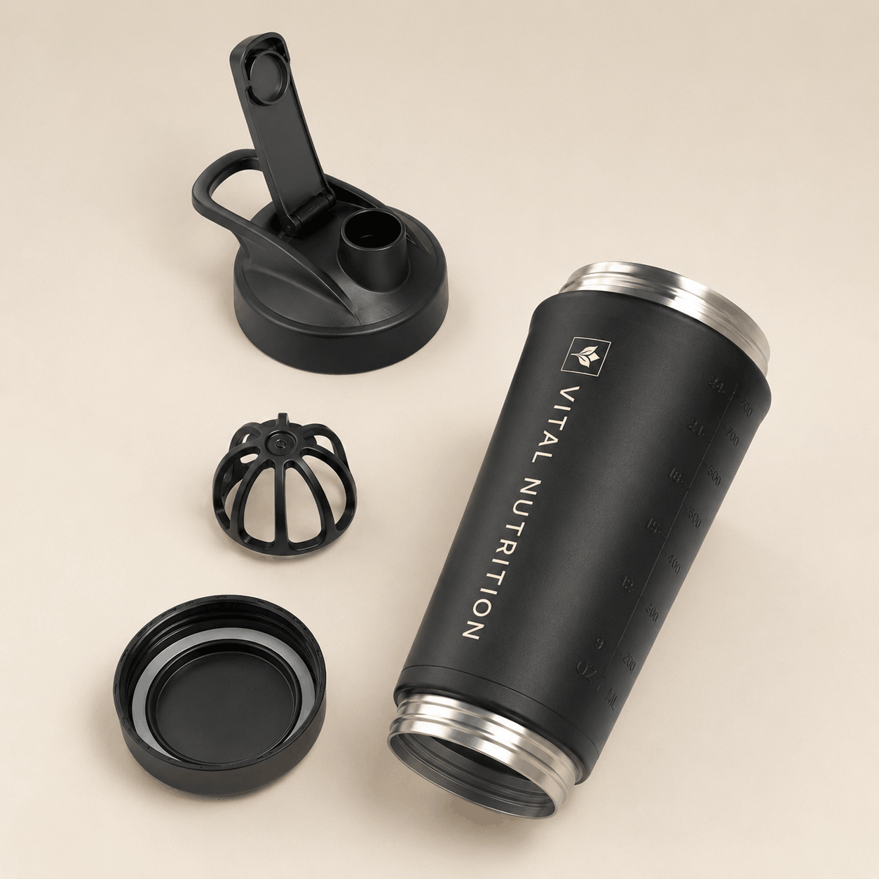Vital Nutrition RVS shaker met losse dop, uitneembaar mixelement en afneembare bodem op een lichte beige achtergrond.