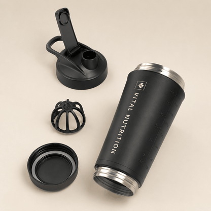 Vital Nutrition RVS shaker met losse dop, uitneembaar mixelement en afneembare bodem op een lichte beige achtergrond.